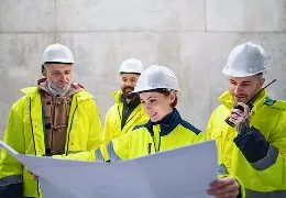 Construction team reviewing plans at a concrete site.