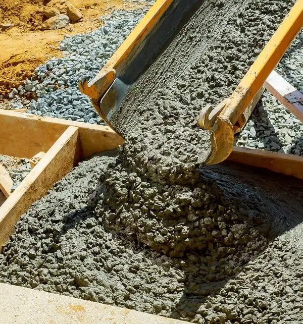 Fresh concrete being poured into a wooden form for construction.