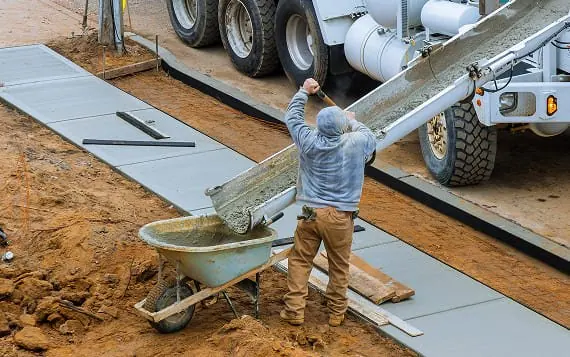 Concrete sidewalk being poured by G&G Concrete Inc at construction site.