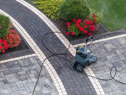 Professional concrete paving with a power washer on a landscaped walkway.