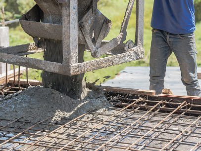 Concrete being poured onto rebar framework for foundation.