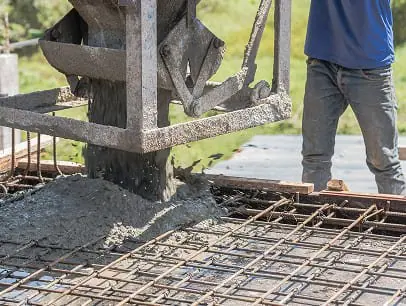 Concrete being poured onto rebar framework for foundation.